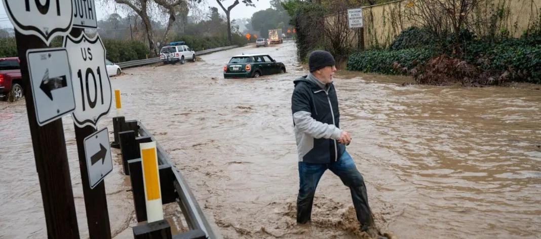 Un ciudadano camina entre una vía totalmente inundada en California