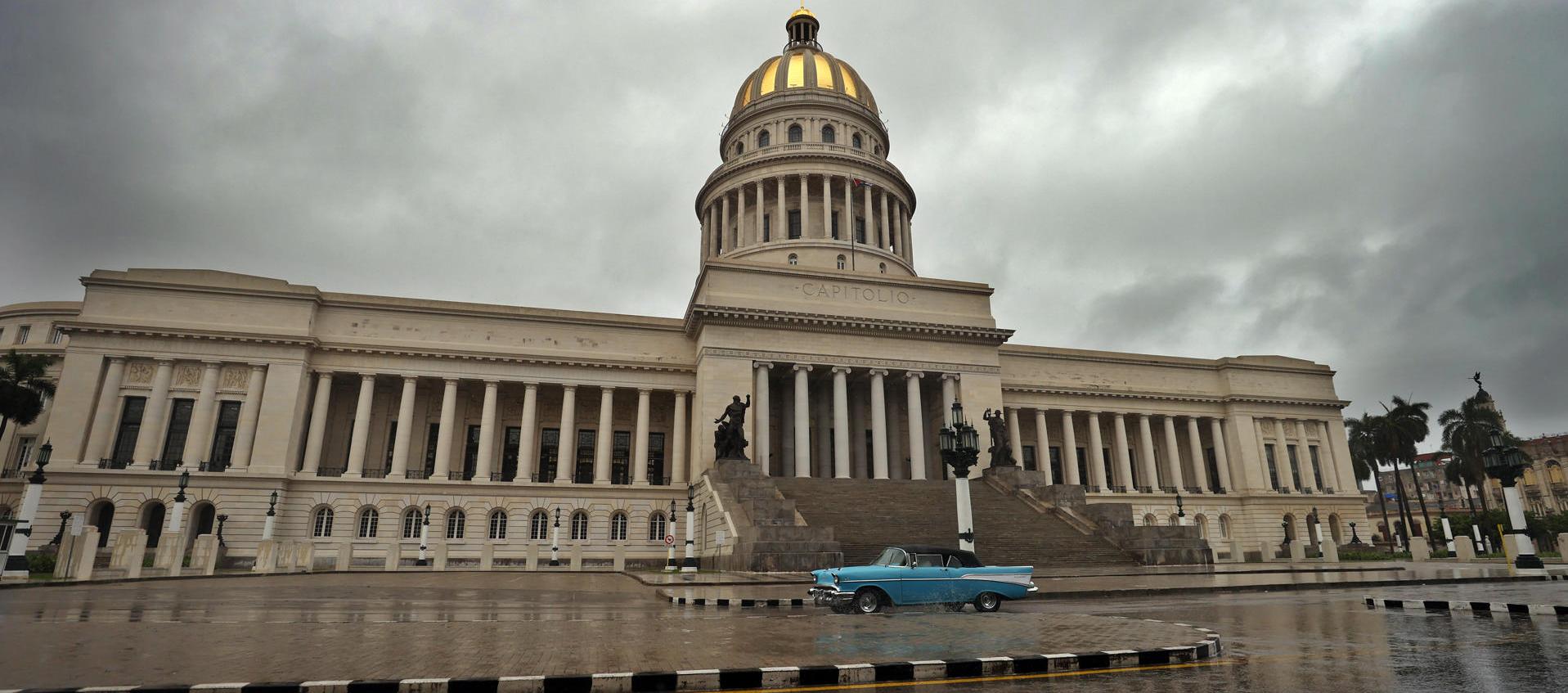 Una persona conduce hoy un vehículo bajo la lluvia, frente al Capitolio en La Habana. 