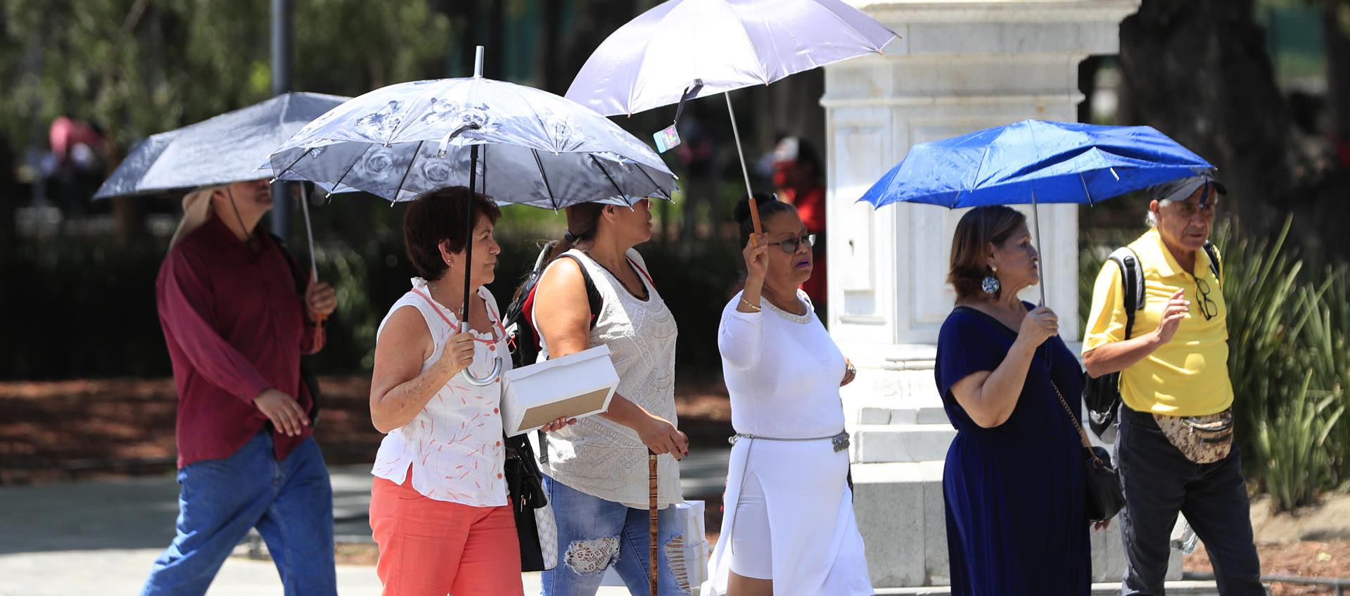Personas se protegen del sol con sombrillas, en la Alameda Central la Ciudad de México 