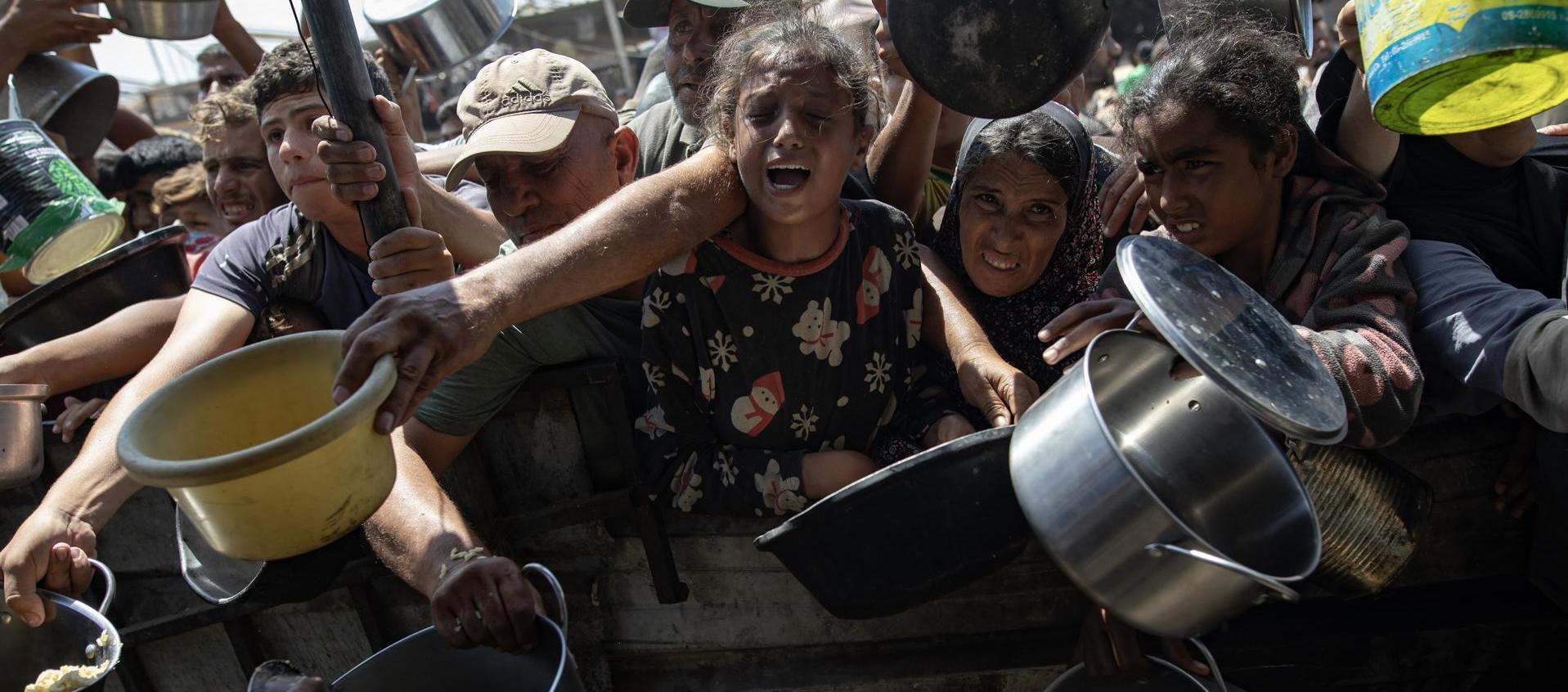 Palestinos desplazados reciben alimentos donados por organización benéfica.