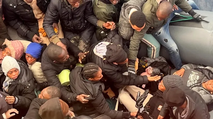 Foto del recién nacido rodeado de hombres y mujeres apiñados en la lancha. 