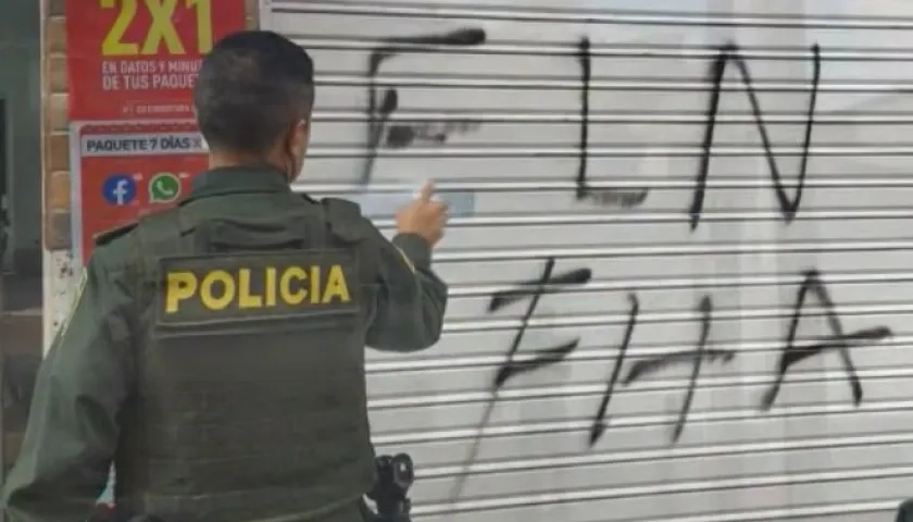 Un policía borra uno de los grafitis del ELN que aparecieron este jueves en Anorí, Antioquia