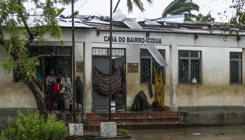 Varias personas se protegen de la lluvia en una calle inundada tras de la destrucción causada por el ciclón Freddy en Quelimane, Mozambique.