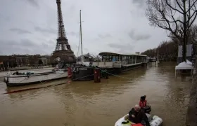 Un hombre transporta a un pasajero en un bote en el desbordado río Sena, París.