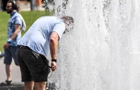 Un hombre se refresca en una fuente ante las altas temperaturas. 
