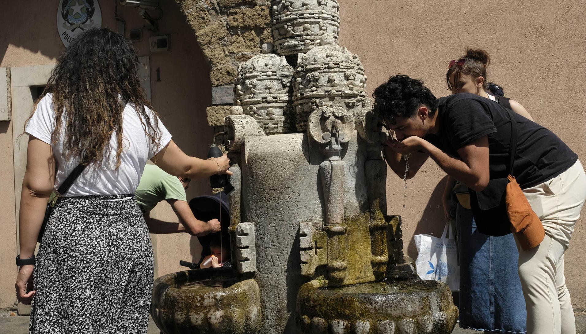 Varias personas se refrescan en una fuente en Roma, Italia.