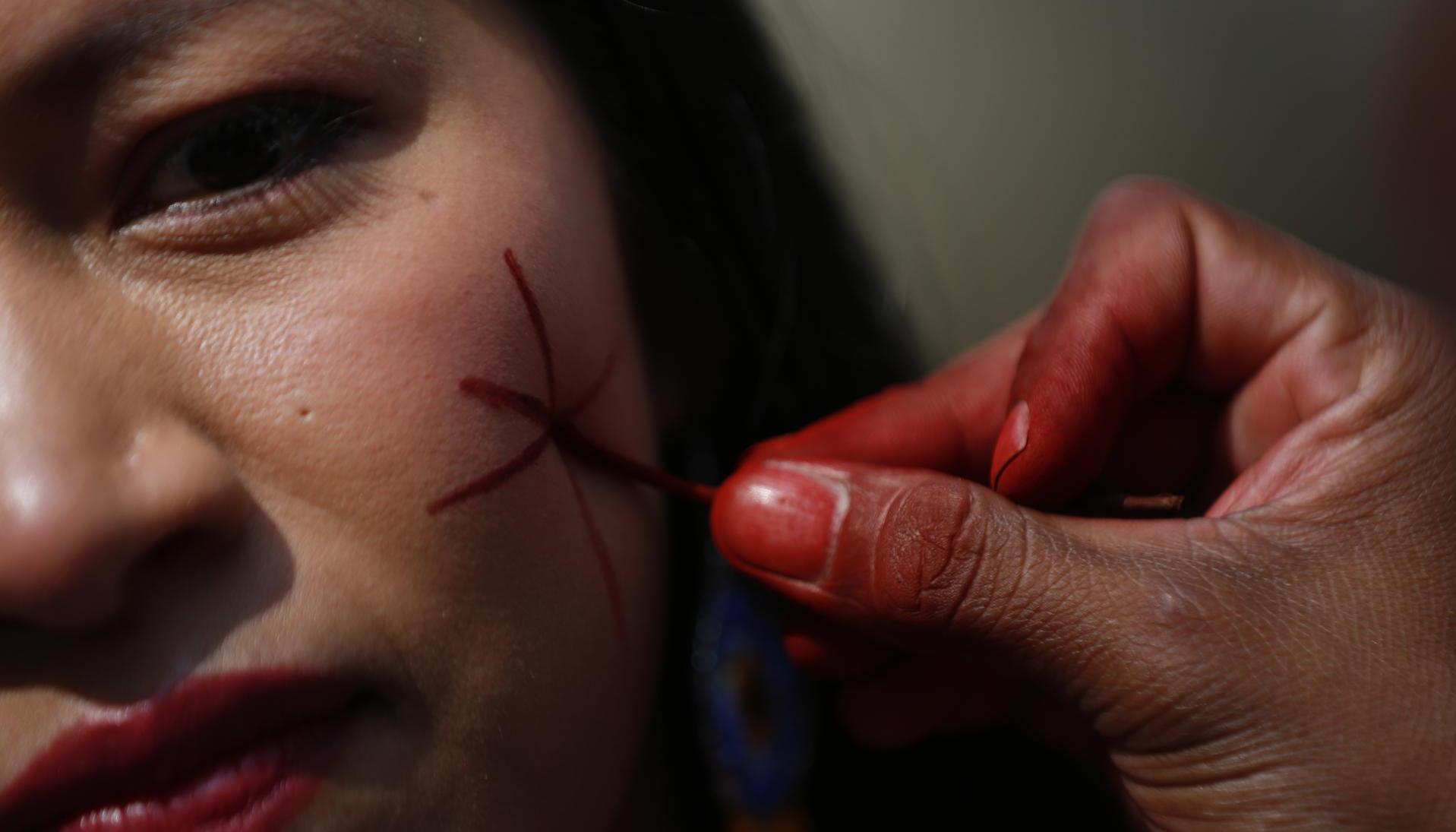 Una mujer indígena se pinta el rostro durante la inauguración de la Zona Verde de la COP16 en Cali.