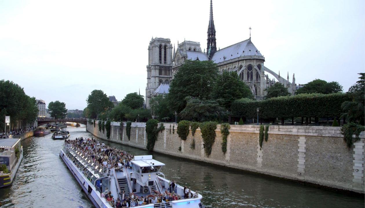 Un barco con turistas navegando por el Sena junto a la catedral de Notre Dame.