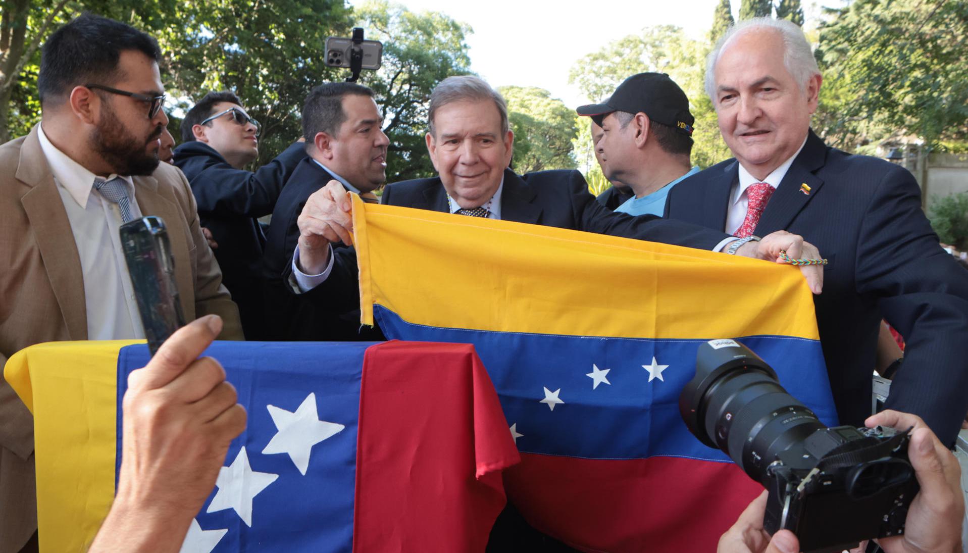 Edmundo González sostiene la bandera de Venezuela en Montevideo, Uruguay.