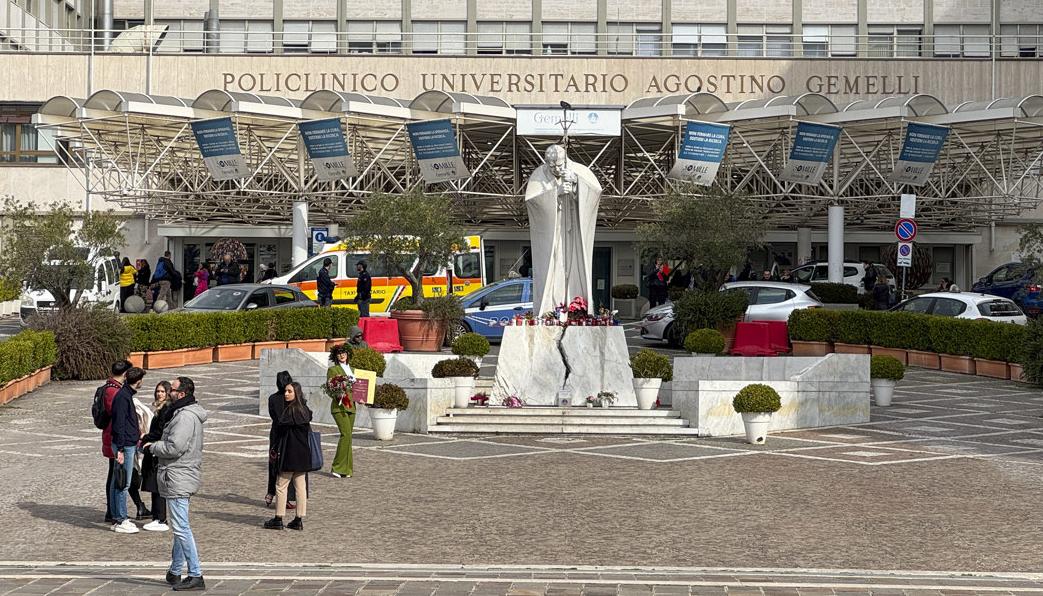 Velas y flores a los pies de la escultura de Juan Pablo II a las puertas del Hospital Gemelli