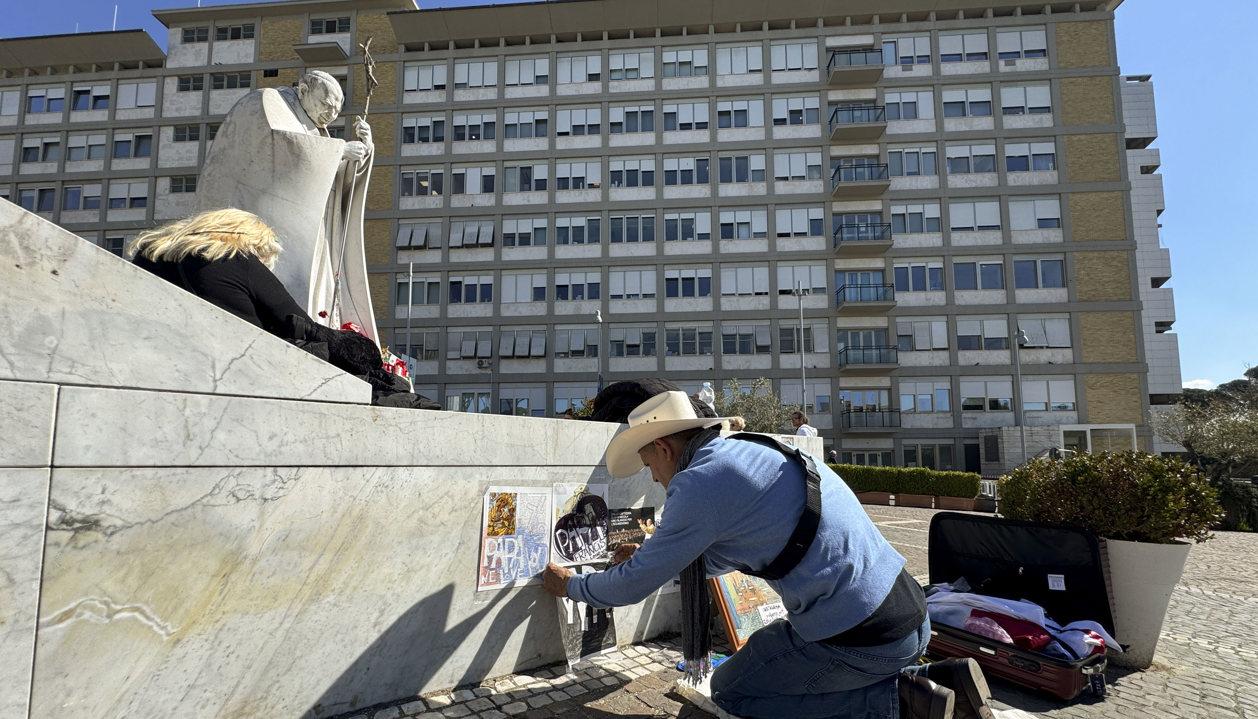 Un artista dibuja ante la escultura del Papa Juan Pablo II, a las puertas del Hospital Gemelli.