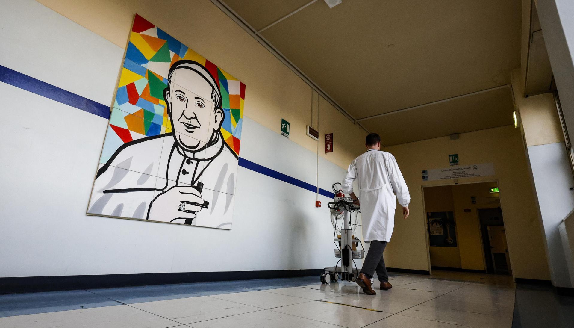 Un médico pasa junto a un mural que representa al Papa Francisco dentro del Hospital Gemelli.