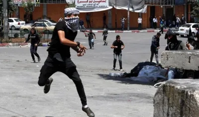 Un palestino arroja piedras contra las tropas israelíes durante un enfrentamiento en la ciudad cisjordana de Hebrón.