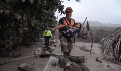 Un trabajador de los equipos de rescate de Guatemala ayuda a una niña en El Rodeo, Escuintla (Guatemala).