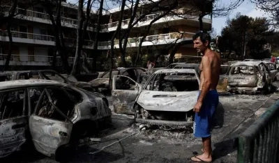 Un residente observa el estado en que han quedado varios coches calcinados tras el paso de las llamas por Mati, barrio del noreste de Atenas (Grecia) .