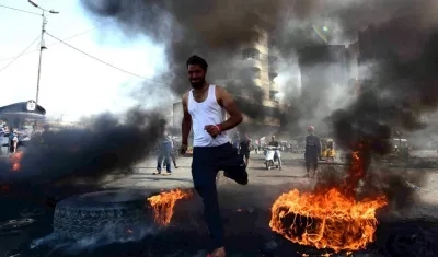 Un manifestante corre entre llantas ardiendo durante una manifestación en la plaza de Khillani en Bagdad, Irak.