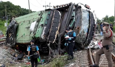La policía tailandesa trata de reunir evidencias en el lugar donde un bus fue arrollado por un tren.