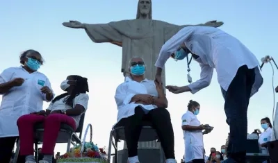 Dos mujeres son vacunadas hoy, lunes en un acto simbólico a los pies de la emblemática estatua del Cristo Redentor en el cerro del Corcovado, en Río de Janeiro. 