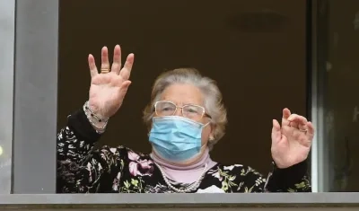 Una señora saluda desde su ventana en una residencia de ancianos. 