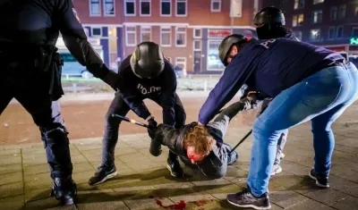 Un hombre es reducido por varios policías durante los disturbios registrados anoche en Rotterdam, Países Bajos. 