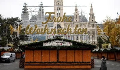 Una mujer camina por un mercado navideño cerrado frente al ayuntamiento de Viena. 