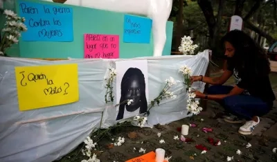 Una mujer deja flores junto a la foto de la niña Maira Alejandra Orobio, asesinada con signos de tortura y abuso sexual en Guapi.