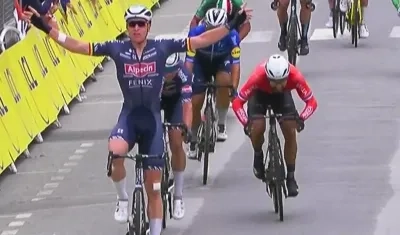 El belga Tim Merlier levanta los brazos en la meta.