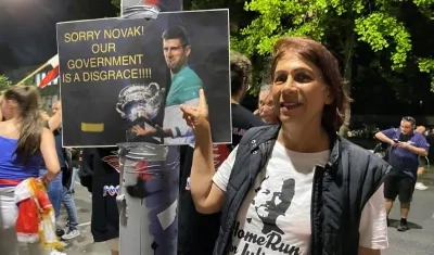 Mujer sostiene cartel en apoyo a Novak Djokovic. 