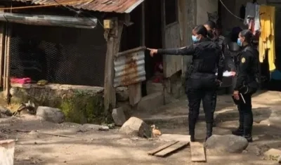 Dos mujeres policías señalan la vivienda en el que fueron hallados los siete cuerpos.