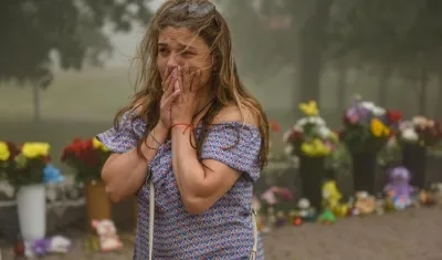 Una mujer llora teniendo de fondo las flores que llevaron al centro comercial de Kremenchuk tras el ataque con misiles.