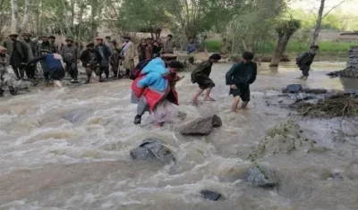 Varias personas atraviesan aguas desbordadas en Afganistán.