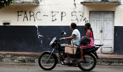 La imagen de archivo muestra a dos ciudadanos de Saravena (Arauca) pasando frente a una pared rayada con las frases FARC y EP.