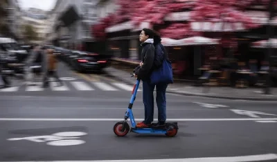 Dos usuarios se movilizan en una patineta eléctrica por las calles de París