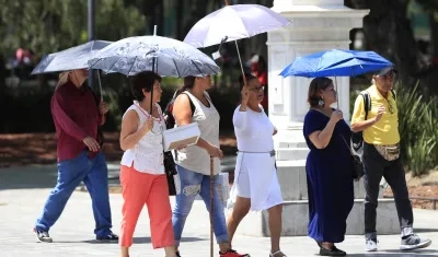 Personas se protegen del sol con sombrillas, en la Alameda Central la Ciudad de México 