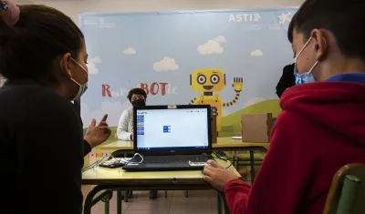 Dos niños manejan un robot por ordenador en un colegio español. 